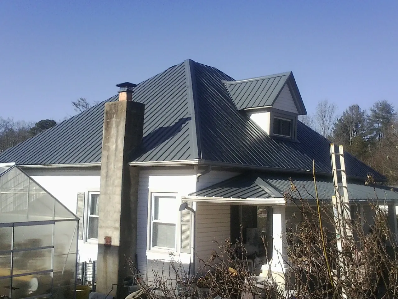 Dark blue standing seam metal roof on a white farmhouse with dormer — Slate & Tile Roof Repair by Roofing Brothers in Sherrills Ford