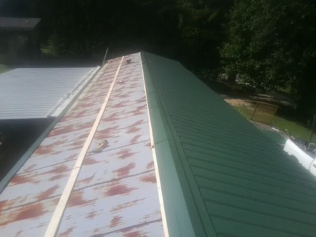 Old rusted panels beside newly installed green metal roofing — Wind Damage Roof Repair by Roofing Brothers in Sherrills Ford