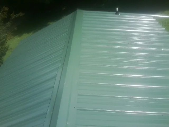 New green metal panels meeting at the ridge of a roof — Flat Roof Repair work by our crew in Sherrills Ford