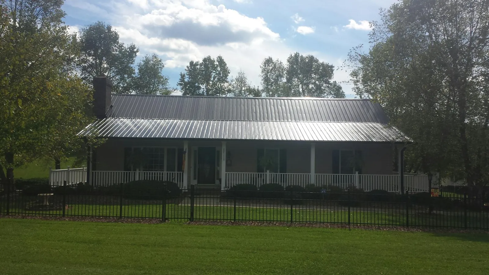 Gray metal roof on a brick ranch with a full width front porch — Gutter Guard Installation work by our crew in Sherrills Ford