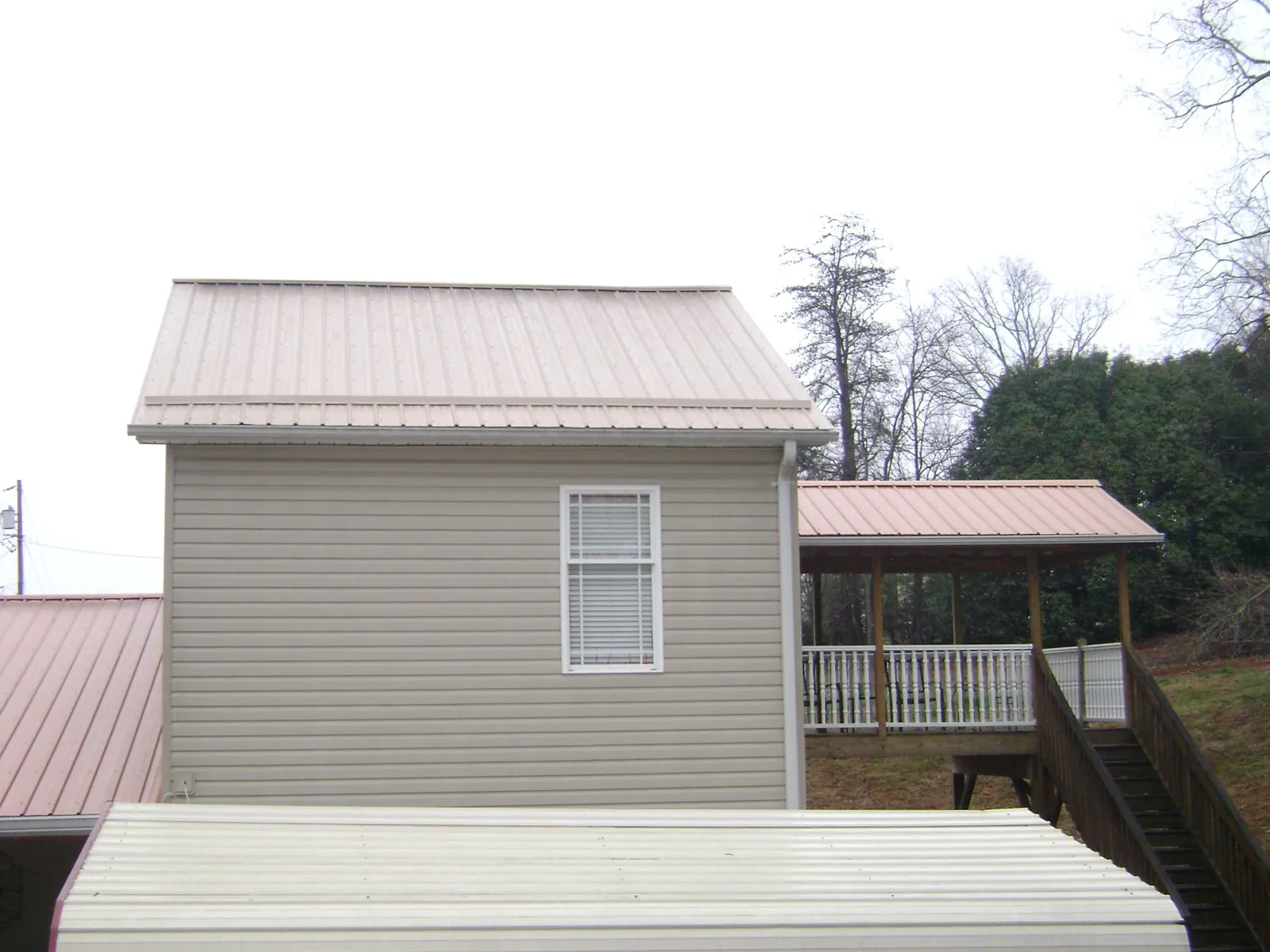 Tan metal roofs on a two story addition and attached porch, from a Roof Replacement job in Sherrills Ford