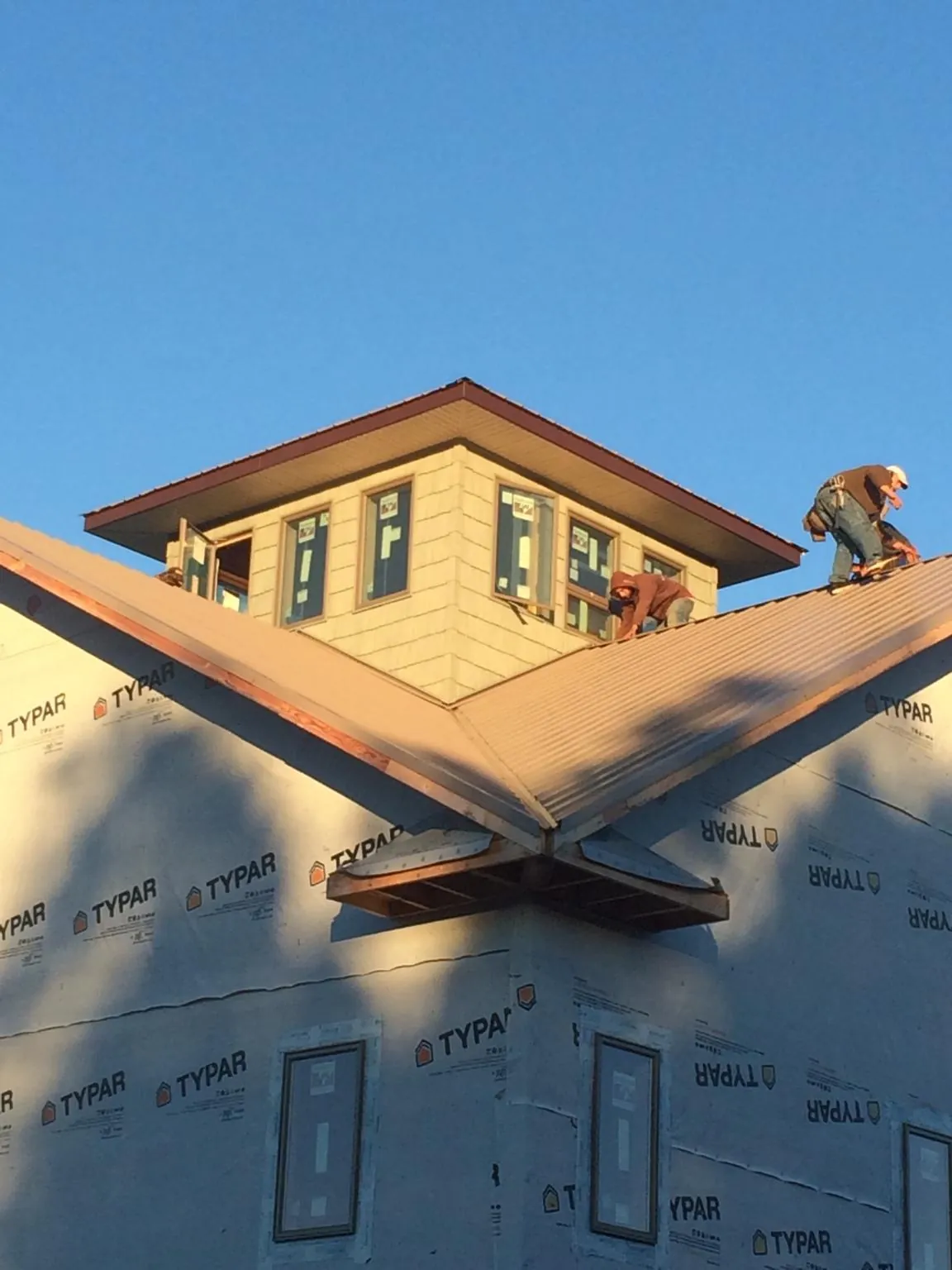 Roofers working around a rooftop cupola on a new metal roof at sunset — Roof Waterproofing in Sherrills Ford by Roofing Brothers